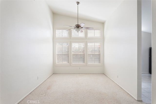 empty room featuring lofted ceiling, carpet, baseboards, and ceiling fan