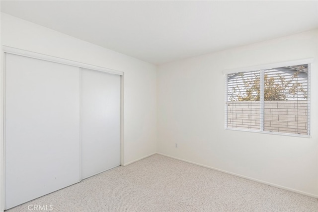 unfurnished bedroom featuring a closet, carpet flooring, and baseboards