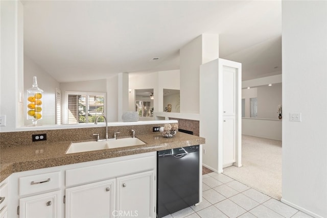 kitchen featuring light tile patterned floors, lofted ceiling, white cabinets, a sink, and dishwasher