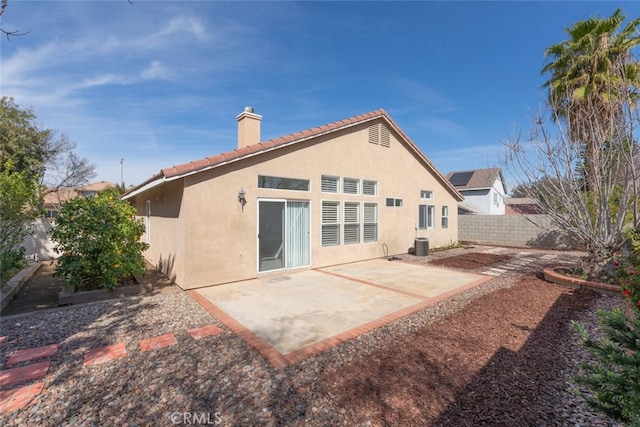 back of house with a tile roof, a chimney, fence, a patio area, and stucco siding