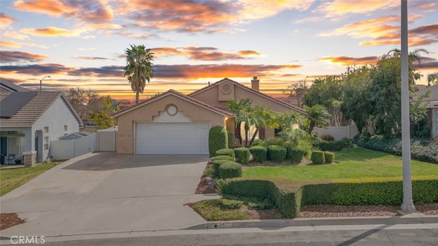 view of front of house featuring an attached garage, fence, driveway, stucco siding, and a front lawn