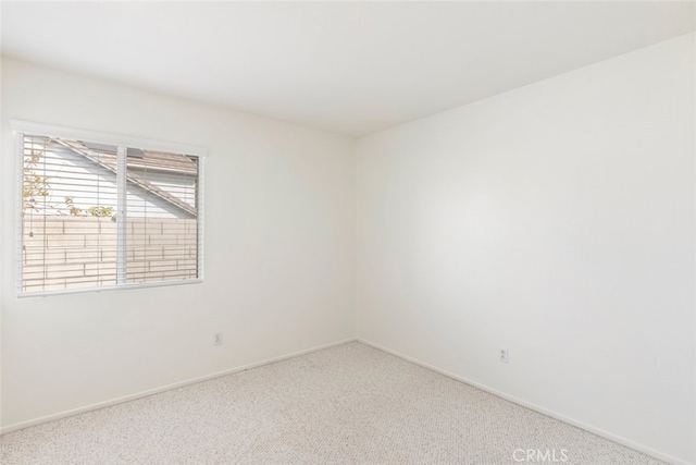 empty room featuring light carpet and baseboards