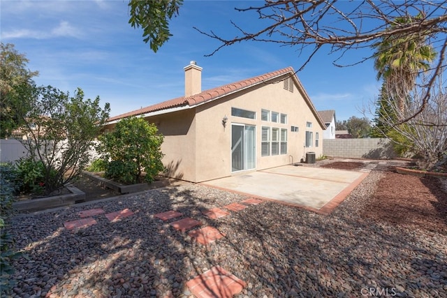 rear view of property featuring a patio, a chimney, stucco siding, fence, and a tiled roof