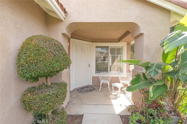 view of exterior entry featuring a porch and stucco siding