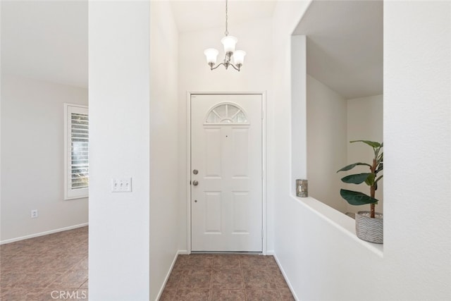 foyer entrance with a notable chandelier and baseboards