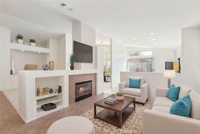 living room featuring built in shelves, recessed lighting, visible vents, a tiled fireplace, and vaulted ceiling