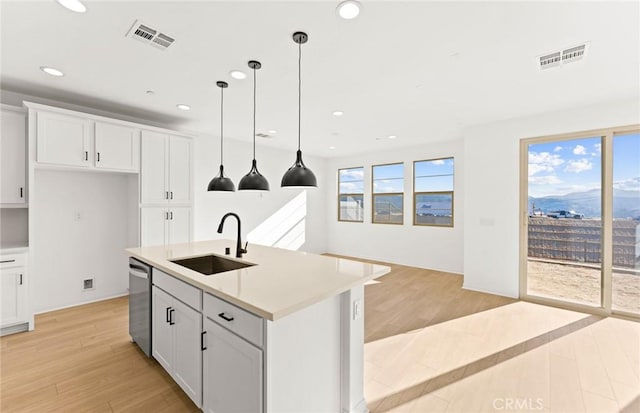 kitchen with sink, stainless steel dishwasher, white cabinets, and a center island with sink