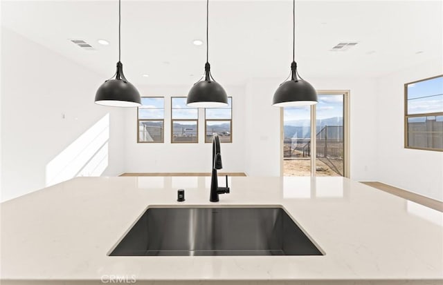 interior details featuring hanging light fixtures, sink, and light stone counters