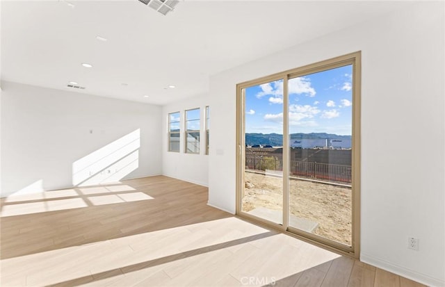 empty room featuring a mountain view and light hardwood / wood-style floors