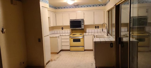 kitchen featuring range with electric cooktop, tile countertops, sink, white cabinets, and stove