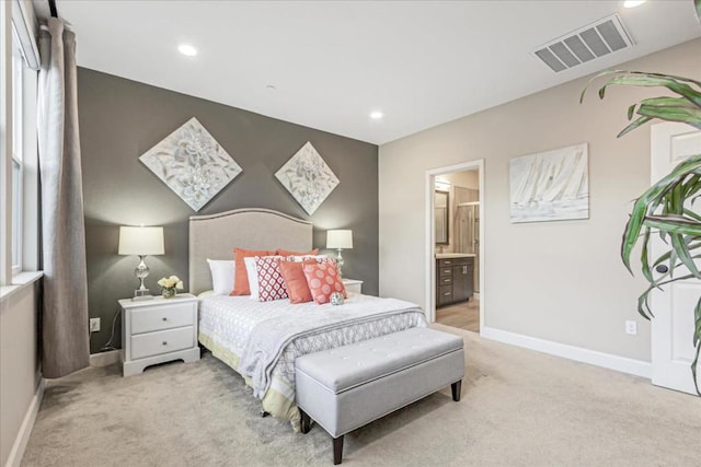 bedroom featuring connected bathroom and light colored carpet