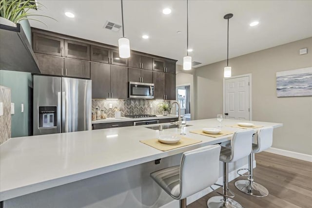 kitchen featuring dark brown cabinetry, appliances with stainless steel finishes, a kitchen island with sink, and sink