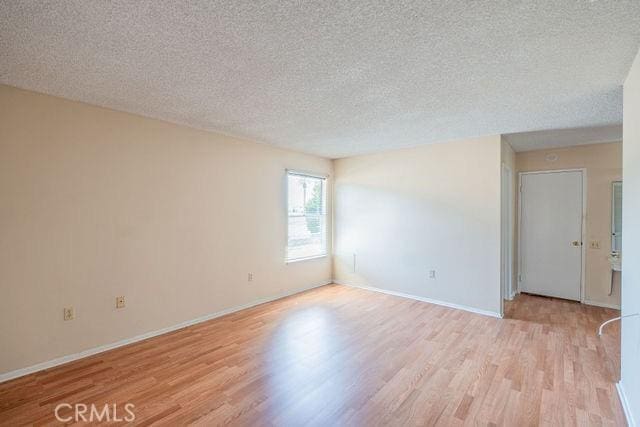 empty room with light hardwood / wood-style flooring and a textured ceiling