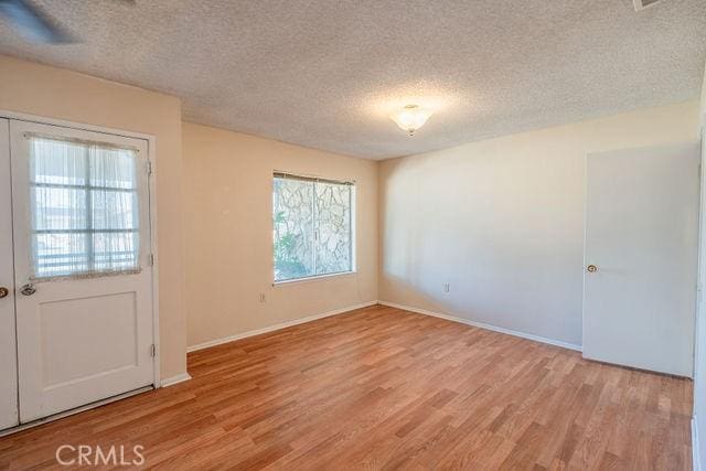 empty room with light hardwood / wood-style flooring and a textured ceiling