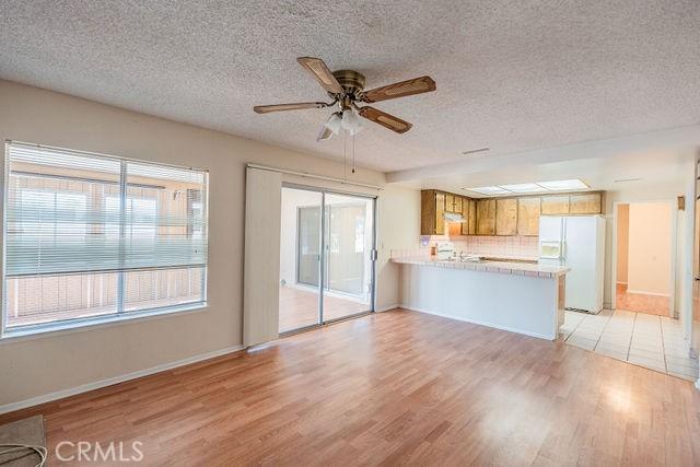 unfurnished living room with a textured ceiling, light hardwood / wood-style floors, and ceiling fan