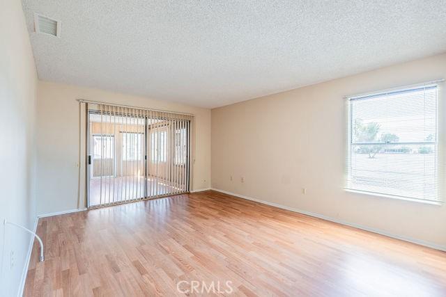 empty room with a healthy amount of sunlight, light hardwood / wood-style flooring, and a textured ceiling