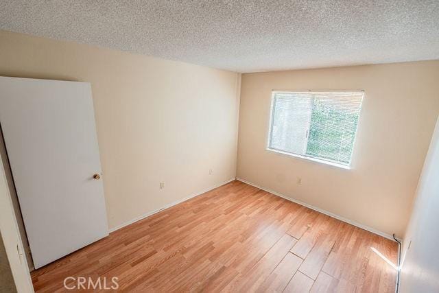 spare room with light hardwood / wood-style flooring and a textured ceiling