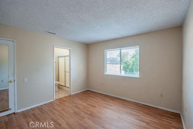 spare room featuring light hardwood / wood-style floors and a textured ceiling