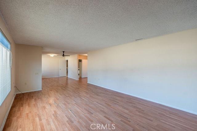 empty room featuring ceiling fan, light hardwood / wood-style flooring, and a textured ceiling