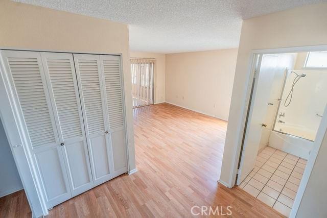 hallway featuring light hardwood / wood-style floors and a textured ceiling