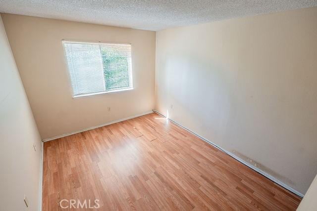 empty room with a textured ceiling and light hardwood / wood-style floors