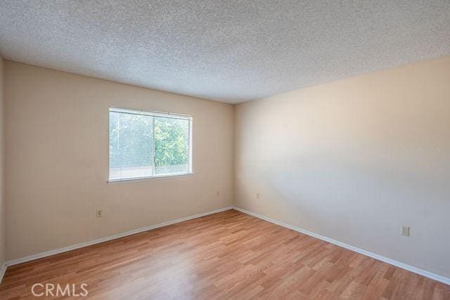 empty room with light hardwood / wood-style flooring and a textured ceiling