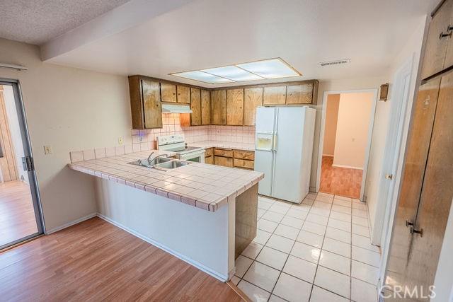 kitchen with sink, tile counters, kitchen peninsula, white appliances, and backsplash