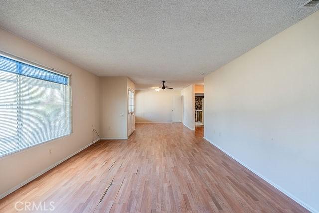 unfurnished room with ceiling fan, a textured ceiling, and light wood-type flooring