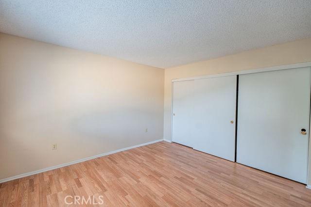 unfurnished bedroom featuring a textured ceiling, light hardwood / wood-style floors, and a closet