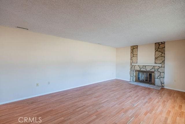 unfurnished living room featuring a textured ceiling, a fireplace, and light hardwood / wood-style flooring