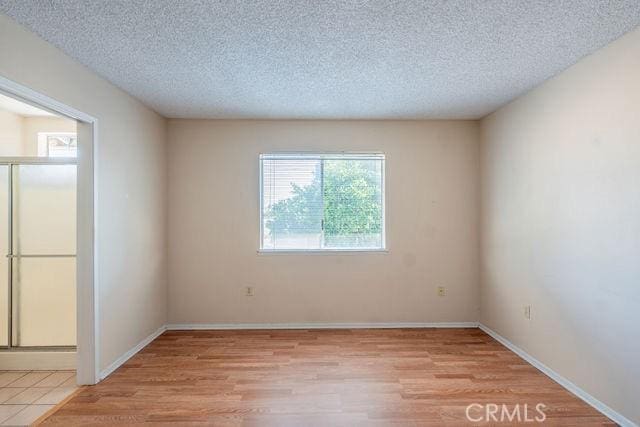 unfurnished room with a textured ceiling and light hardwood / wood-style flooring