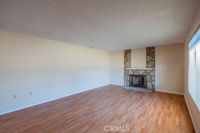 unfurnished living room featuring a stone fireplace, a textured ceiling, and light hardwood / wood-style flooring