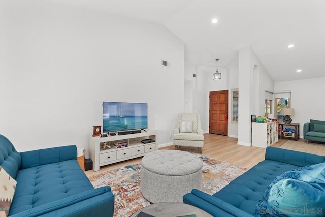 living room featuring high vaulted ceiling and light hardwood / wood-style floors