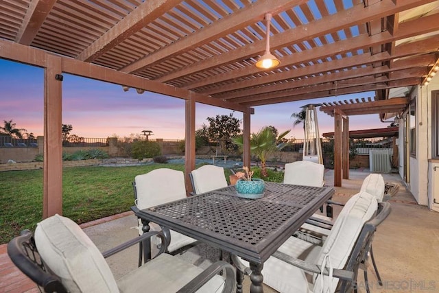 patio terrace at dusk featuring a yard and a pergola