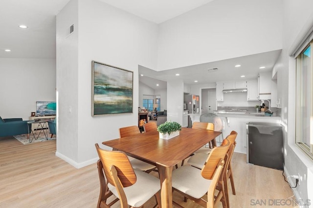 dining area with a high ceiling and light hardwood / wood-style flooring