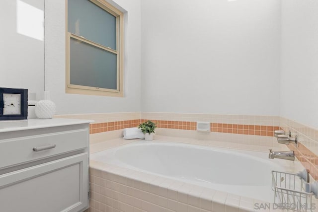 bathroom with tiled tub and vanity