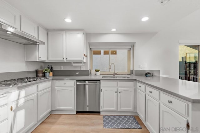 kitchen with sink, light hardwood / wood-style flooring, appliances with stainless steel finishes, white cabinets, and kitchen peninsula