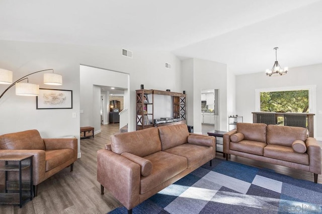 living room featuring lofted ceiling, hardwood / wood-style flooring, and a chandelier