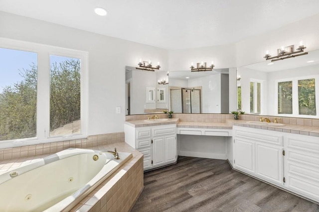 bathroom with vanity, hardwood / wood-style flooring, a wealth of natural light, and separate shower and tub