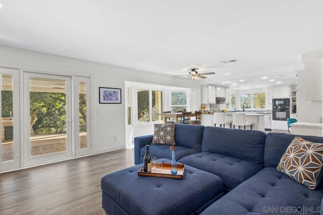 living room with dark wood-type flooring and ceiling fan