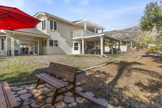 back of property with a patio, a balcony, a yard, and a mountain view