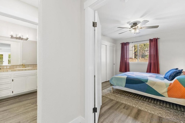 bedroom featuring ensuite bathroom, sink, ceiling fan, and light wood-type flooring