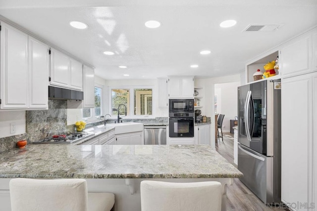 kitchen featuring white cabinetry, sink, black appliances, and kitchen peninsula