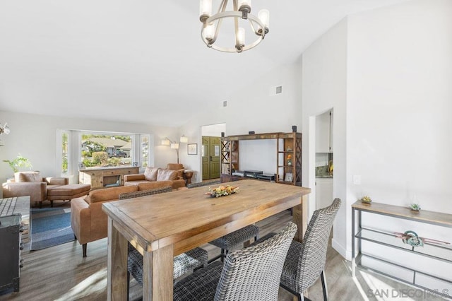 dining room with an inviting chandelier, wood-type flooring, and high vaulted ceiling