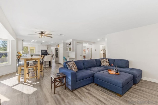 living room featuring sink, light hardwood / wood-style floors, and ceiling fan