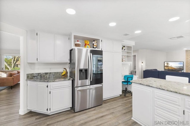 kitchen featuring white cabinetry, light hardwood / wood-style flooring, dark stone counters, and stainless steel fridge with ice dispenser