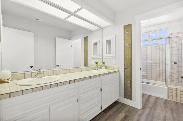 bathroom with enclosed tub / shower combo, wood-type flooring, and vanity