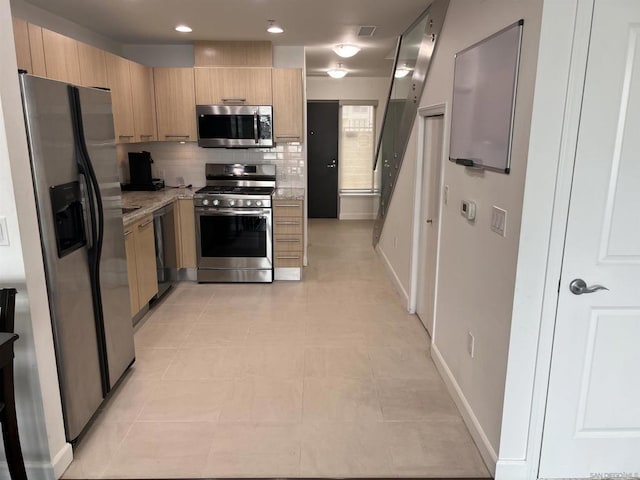 kitchen featuring appliances with stainless steel finishes, light brown cabinetry, light stone countertops, and backsplash