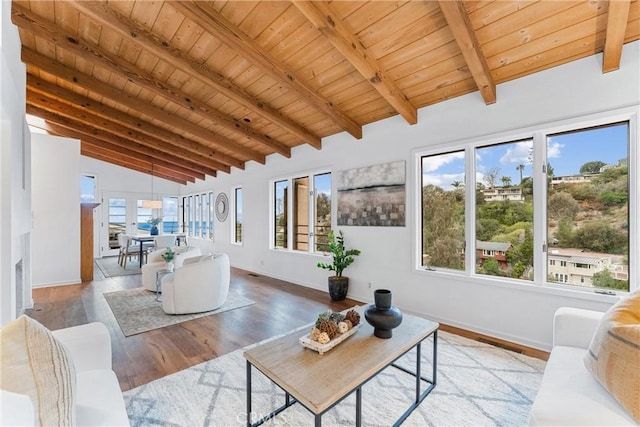 living area with vaulted ceiling with beams, light wood finished floors, wood ceiling, and plenty of natural light