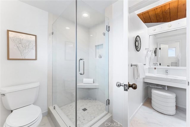 bathroom featuring toilet, marble finish floor, baseboards, and a stall shower